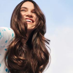 Woman with long, glossy, brunette hair smiles as she looks off into the distance.Woman with long, glossy, brunette hair smiles as she looks off into the distance.