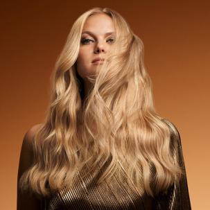 Model with long, blonde hair styled in glossy waves.