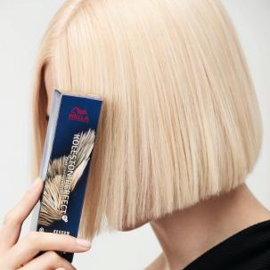 Side profile of a model with short platinum blonde hair concealing their face with a box of Koleston Perfect hair colour by Wella Professionals