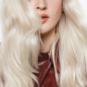 Close-up of the lengths and ends of a model’s icy blonde, wavy hair. 