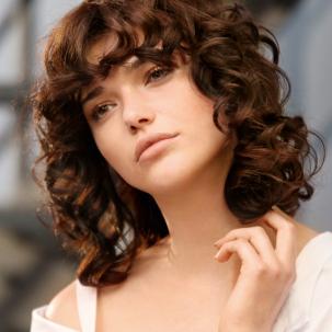 Woman with brown curly perm with fringe
