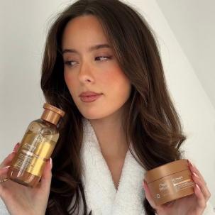 Model with long, brown hair holding ULTIMATE SMOOTH Shampoo and ULTIMATE SMOOTH Mask.