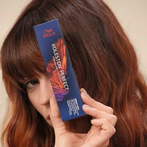 Woman with auburn hair holds a Koleston Perfect box in front of her face.