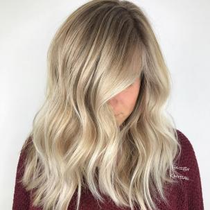 Woman with mid length, beige blonde hair styled with loose waves