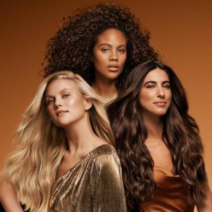 Three models with glossy, smooth hair. One has long, curly, espresso brown hair, one has long, wavy, blonde hair, and one has long, wavy, chocolate brown hair.