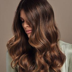 Headshot of a person with long, wavy light brown hair looking down.