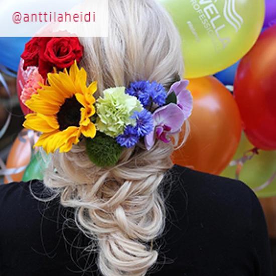 Back of model's head wearing flowers in the colors of the rainbow