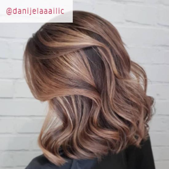 Side profile of woman with with wavy, light brown hair and blonde balayage, created using Wella Professionals.