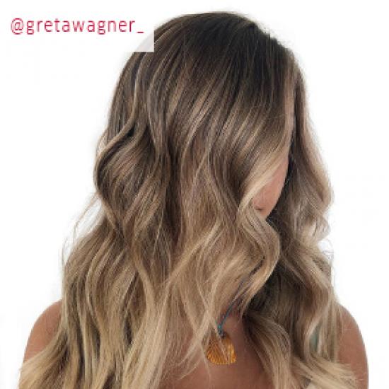 Woman with long, wavy hair and blonde balayage, created using Wella Professionals. 