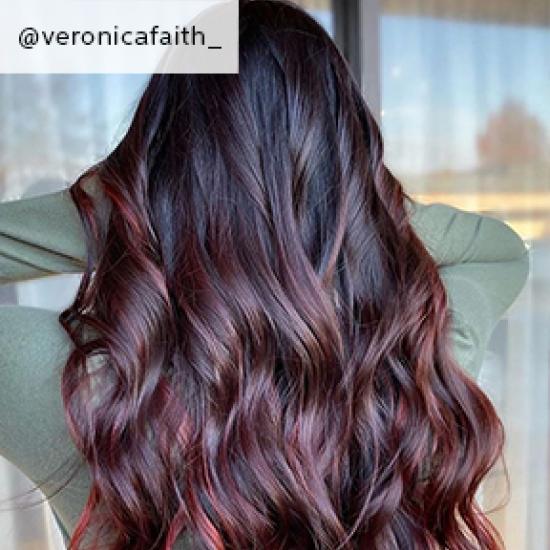 Woman with long hair in burgundy balayage styled with loose waves