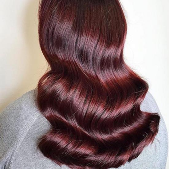 Woman with long, wavy hair in burgundy colour 