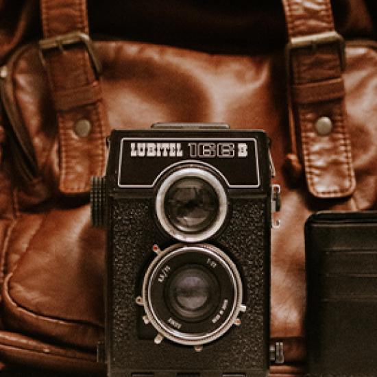 Old photo camera and a brown bag in the background