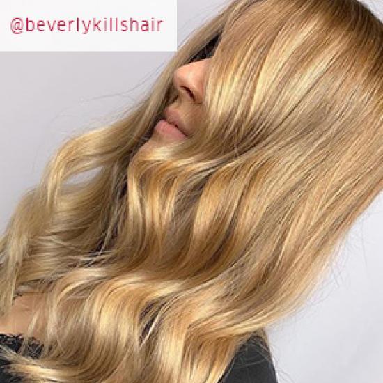 Side profile of woman with long, honey blonde, wavy hair, created using Wella Professionals.