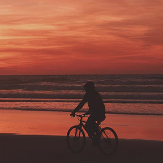 Man on bike in front of red sky