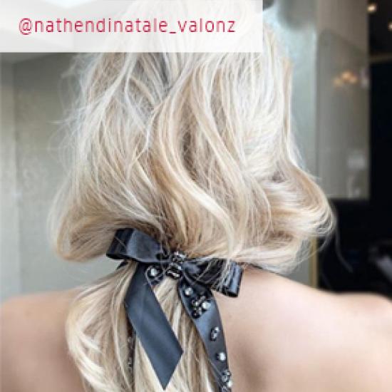 Back of womans head with pearl blonde hair in a black ribbon bow