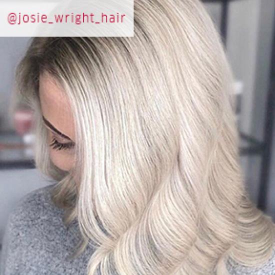 Close up image of woman facing down with curled pearl blonde hair