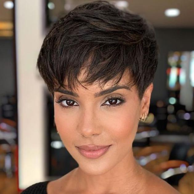 Model with dark brown pixie haircut, featuring subtle caramel highlights.