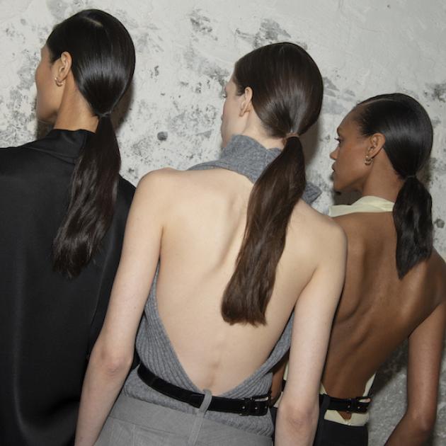 Three models show their low, sleek ponytails backstage at Victoria Beckham FW25.