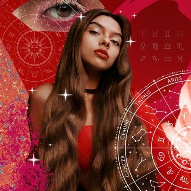 Model with very long brown hair is dressed in red and surrounded by zodiac sign illustrations and stars