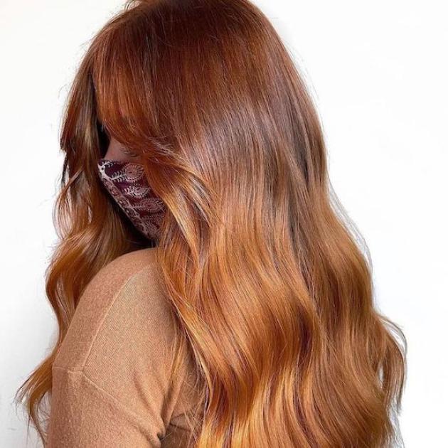 Side profile of person with long, wavy hair and copper balayage.