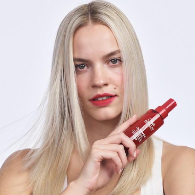 Model with long, straight, blonde hair holds a bottle of ULTIMATE REPAIR Miracle Hair Rescue.