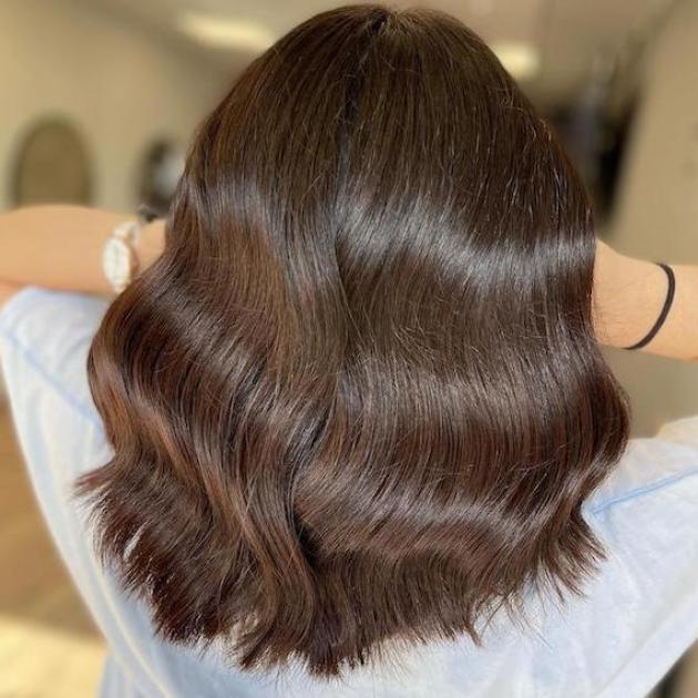 Back of woman’s head with mid-length, dark brown, wavy hair, created using Wella Professionals.