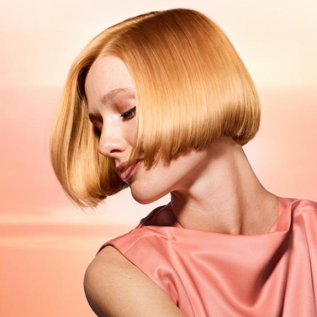 Side profile of model with ultra-glossy, glassy, apricot blonde hair.