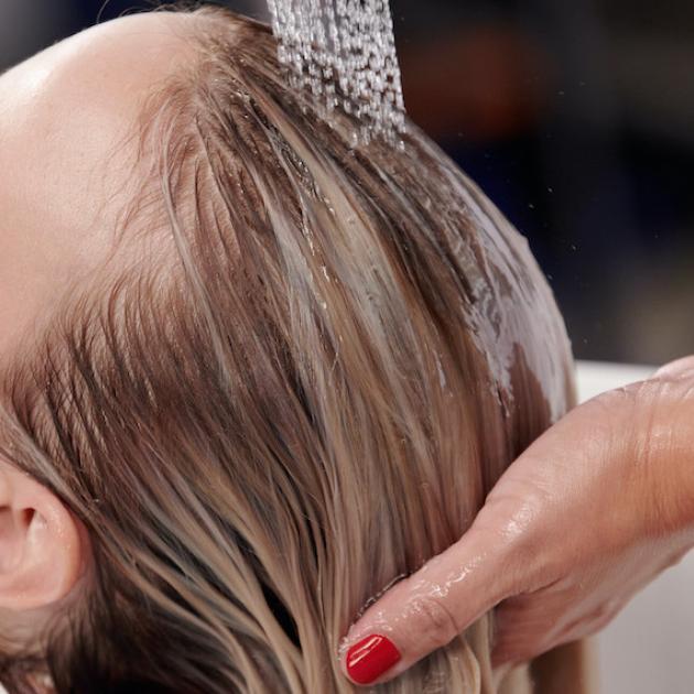 Model’s blonde hair is washed at the sink.