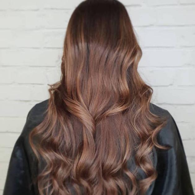 Back of woman’s head with long, loosely-curled, brunette hair, created using Wella Professionals. 