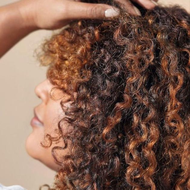 Side profile of model with curly, brown hair and caramel highlights.