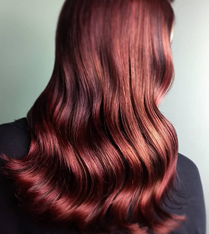 Back of woman’s head with long, loosely-curled, chestnut auburn hair, created using Wella Professionals.