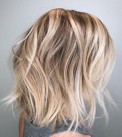 Hinterkopf einer Frau mit blondem, messy Balayage-Bob, kreiert mit Wella Professionals.