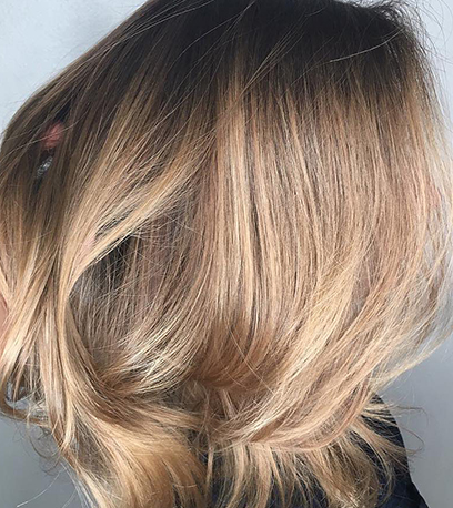 Side profile of woman with glossy, straight, golden balayage bob, created using Wella Professionals.