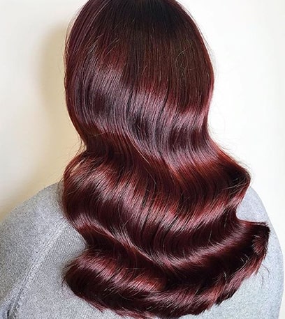 Woman with long, wavy hair in burgundy colour
