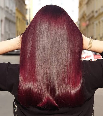 Woman with long sleek burgundy hair created with Wella Professionals