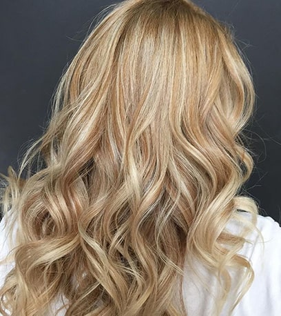 Photo of the back of a woman’s head with warm blonde highlights, created using Wella Professionals.