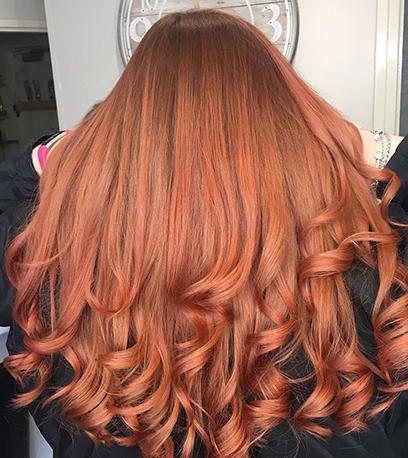 Back of woman’s head with long, wavy, copper red hair, created using Wella Professionals.