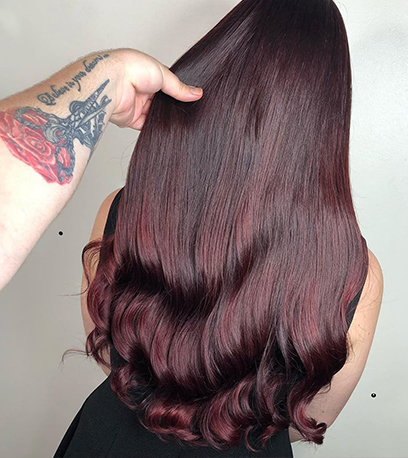 Back of woman’s head with sleek dark purple hair, created using Wella Professionals.