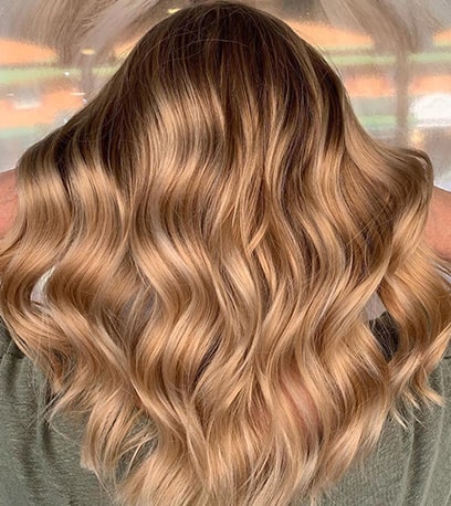 Back of woman’s head with long, golden blonde, wavy hair, created using Wella Professionals. 