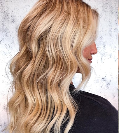Side profile of woman with long, beachy, golden blonde hair, created using Wella Professionals. 
