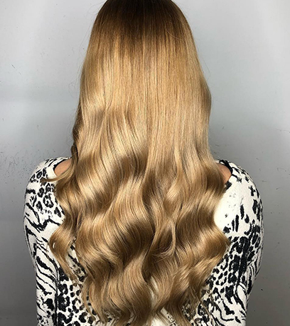 Back of woman’s head with long, loosely curled, golden blonde hair, created using Wella Professionals. 