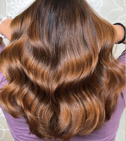 Back of woman’s head with long, golden brown brown, wavy hair, created using Wella Professionals. 