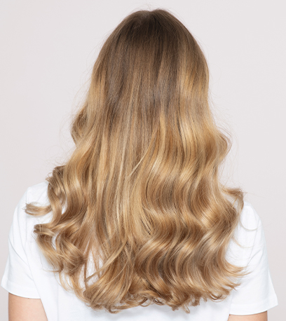 Model with long, wavy, golden blonde hair and Illuminage, created using Wella Professionals.