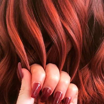 Fingers holding wavy leather red hair, created using Wella Professionals