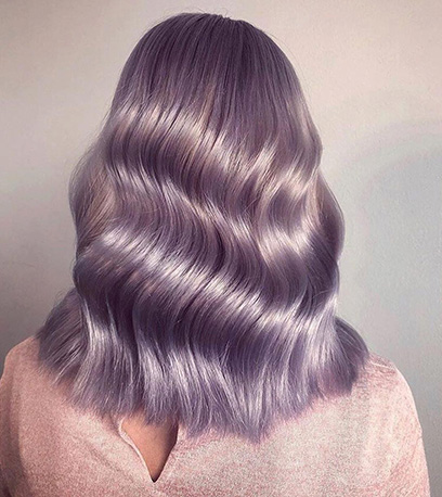 The back of a person's head. They have glossy lilac hair styled in loose waves