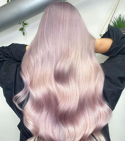 The back of a person's head. They have long light lilac hair styled in loose waves