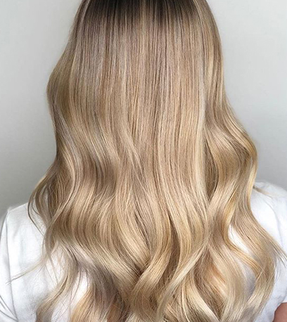 Back of woman’s head with wavy, sandy blonde hair, created using Wella Professionals.