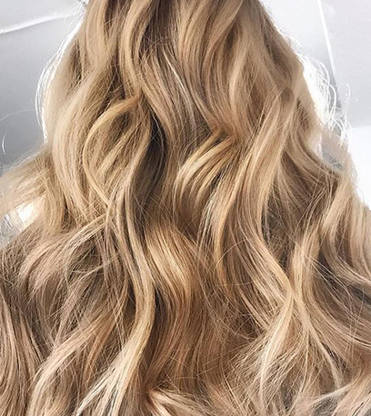 Back of woman’s head with wavy, sandy blonde hair, created using Wella Professionals.