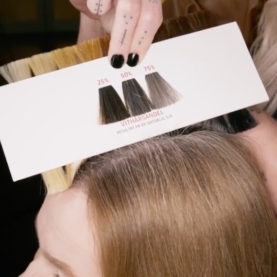 Wella Professionals colorist using the shade selector to determine the volume of gray hairs. 